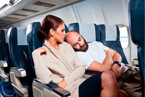 man sleeping on woman's shoulder on airplane