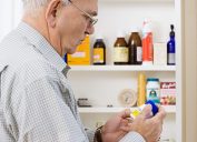 A senior man looking at bottles of medicine and medication in his medicine cabinet