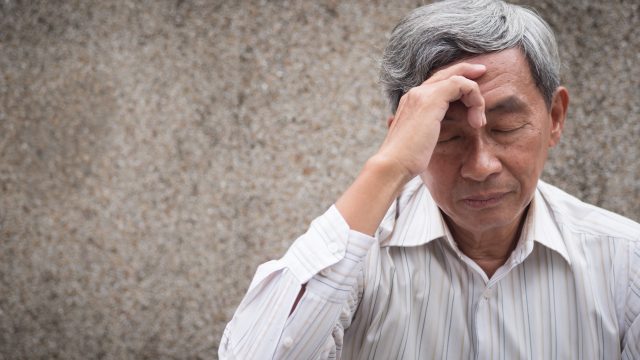 older man holding his head in pain