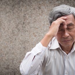 older man holding his head in pain