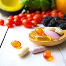 Pills and capsules in wooden spoon with fresh fruit