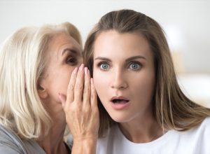 older woman telling secret to younger woman