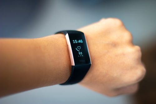 Woman monitoring her heart beat with a fitbit charge 3 activity tracker wearable device on her wrist