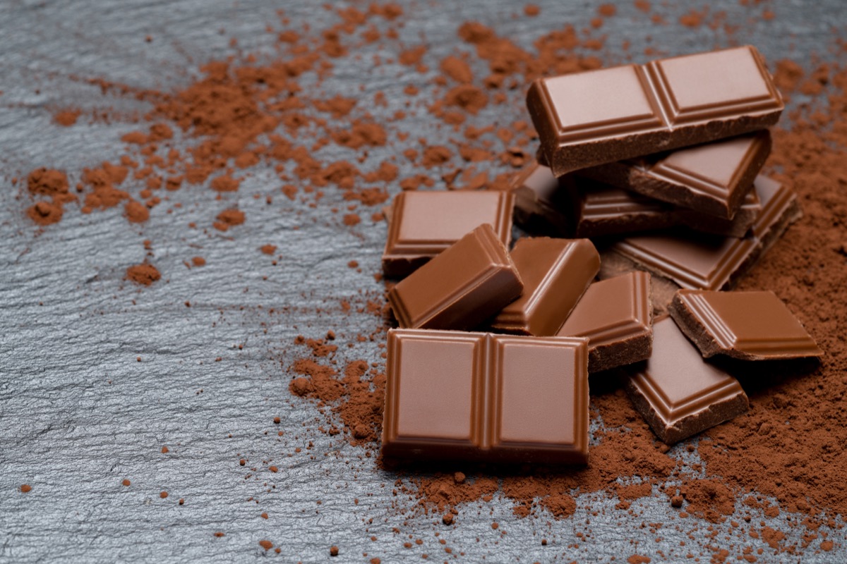 Stücke von dunkler Bio-Schokolade oder Milch- und Kakaopulver auf dunkler Betonpagonda