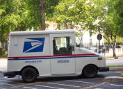 USPS truck parked on street with trees