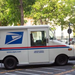 USPS truck parked on street with trees