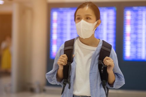 หญิงสาวสวมหน้ากากอนามัยเพื่อป้องกัน coronavirus ในสนามบิน