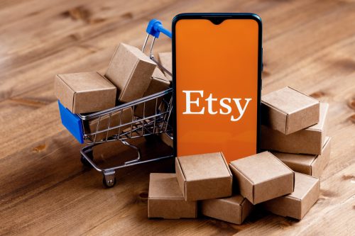Etsy logo on phone screen with mini packages and shopping card