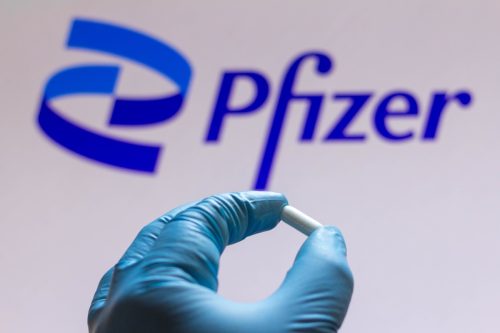 Pfizer logo with gloved hand holding pill