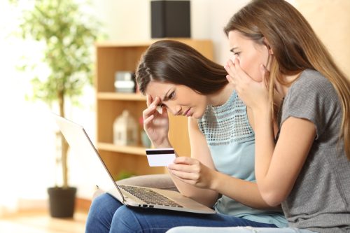 two girls looking concerned at laptop with credit card