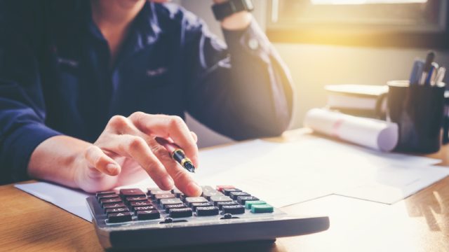 close up of man on calculator doing taxes at his desk