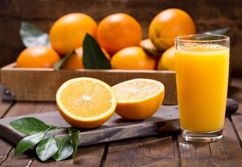 Felii de portocale lângă un pahar de suc de portocale