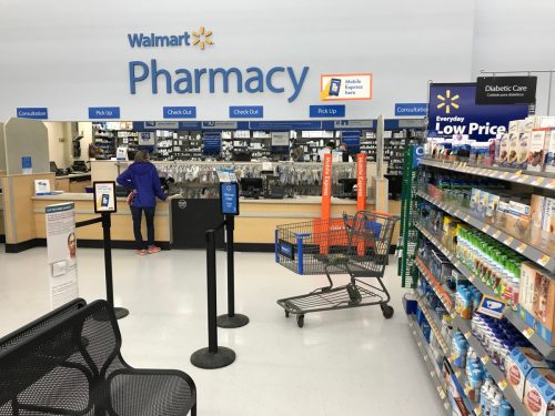Vedere frontală a farmaciei de la Walmart.  Client așteaptă ridicarea.