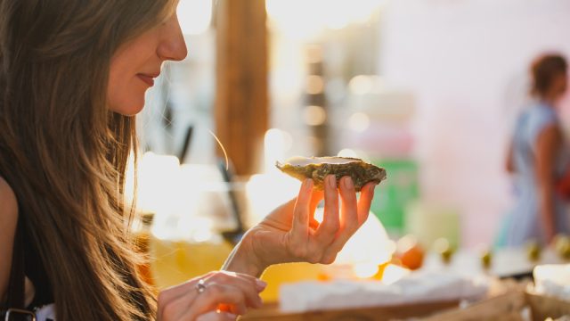 A young woman eating an oyster out of the shell