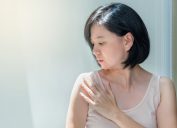 asian woman examining her shoulder skin looking concerned