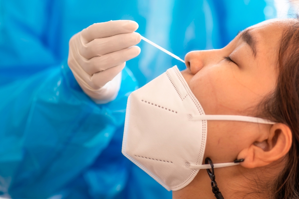 Uma mulher recebendo um cotonete nasal de um profissional de saúde como parte de um teste COVID-19