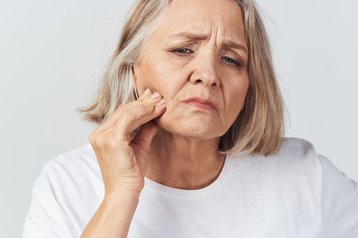 older woman touching her jaw looking concerned