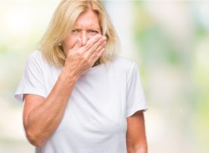 older white woman covering her mouth and holding her nose