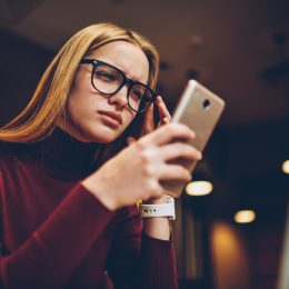 A young woman looking at her smartphone with a confused or concerned look on her face