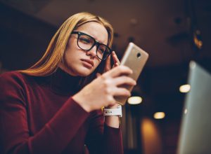 A young woman looking at her smartphone with a confused or concerned look on her face
