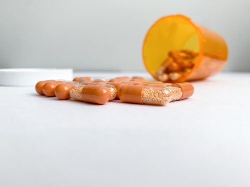 Orange and clear capsules of Amphetamine salts, Adderall XR 30 mg pills spilling out of orange pill bottle.