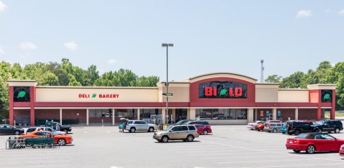 A Bi-Lo supermarket in Spindale, showing parking lot, store front, and people loading food into their cars..