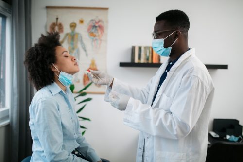 O femeie este examinată într-o clinică medicală pentru depistarea virusului corona și un test cu tampon nazal