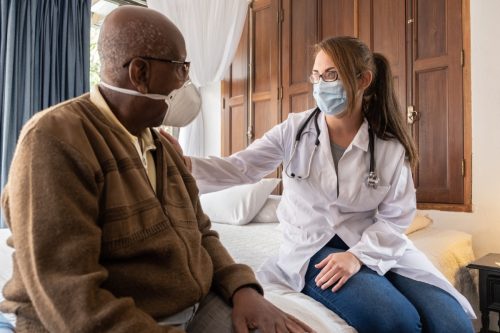 Arzt tröstet einen großen Patienten zu Hause - mit Gesichtsmaske