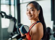 smiling asian woman lifting weights