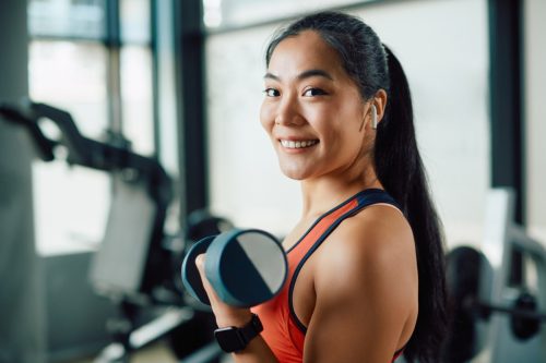 smiling asian woman lifting weights