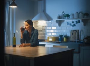 woman drinking wine alone in her kitchen