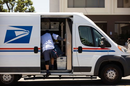 A USPS Postal worker delivers mail.