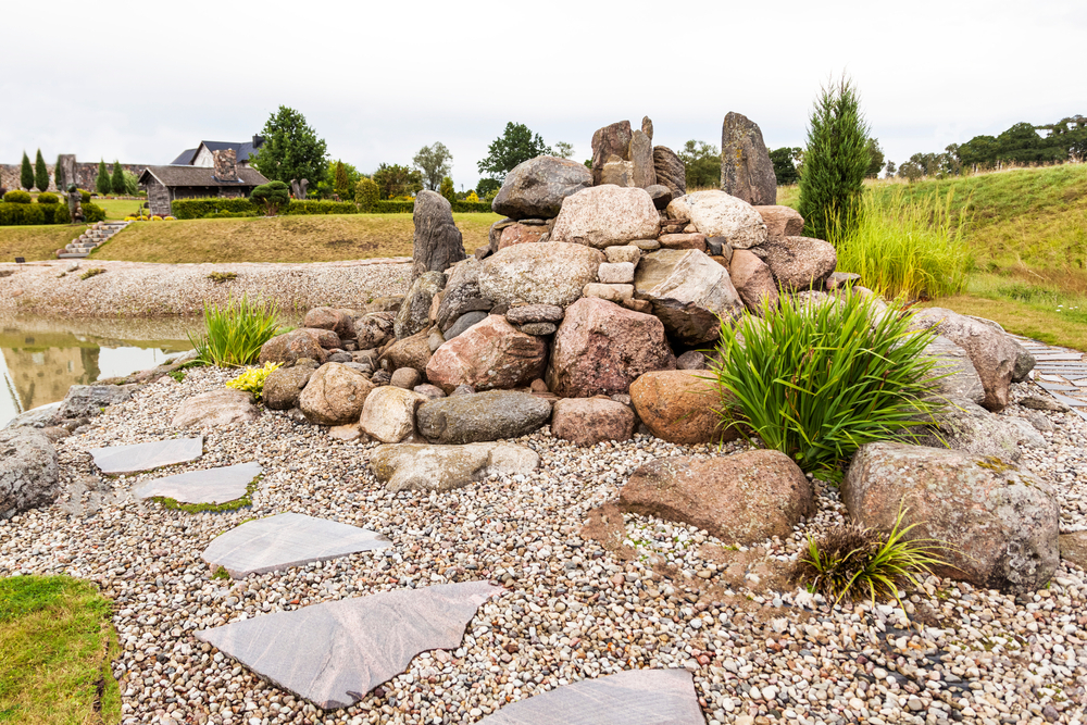 A rock pile in a yard next to a koi pond