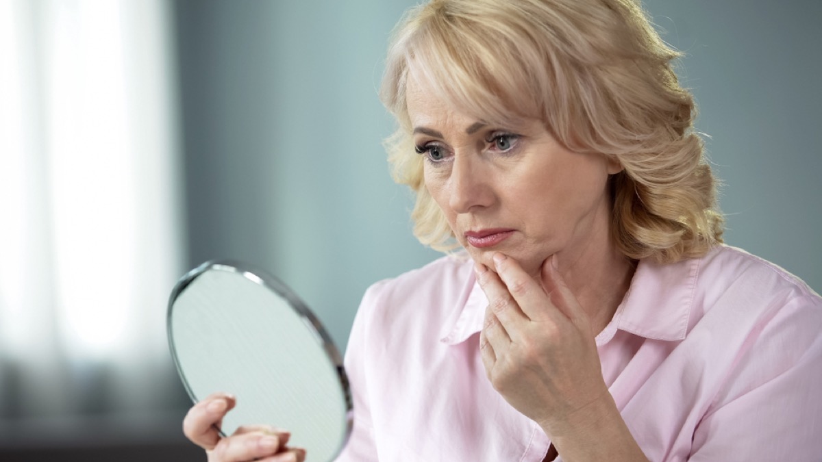 older woman looking concerned in mirror