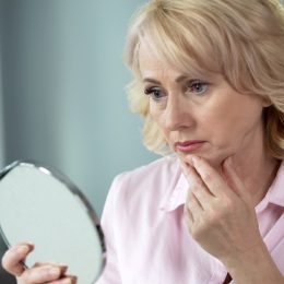older woman looking concerned in mirror