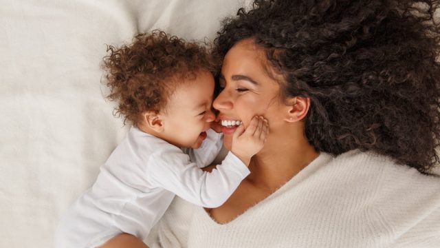 mother smiling at baby in bed