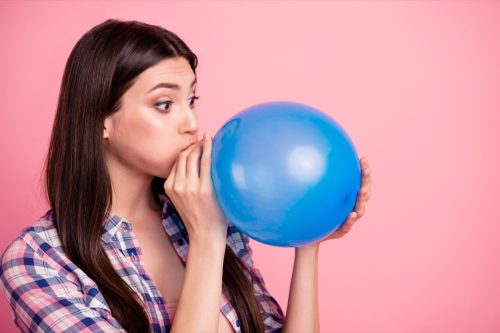 woman blowing up balloon