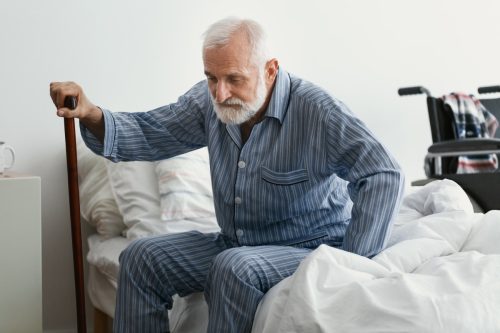senior man in pajamas getting out of bed
