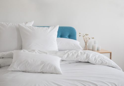 Бели јастуци на кревету са плавим узглављем