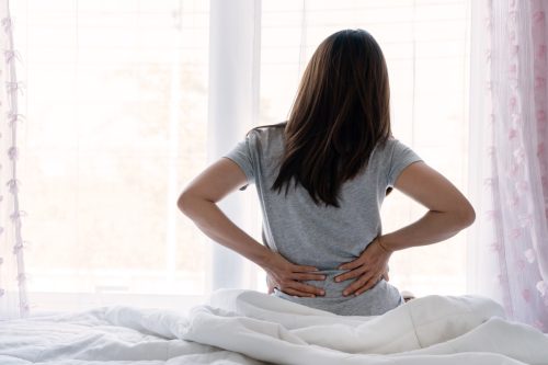 woman waking up in bed with back pain
