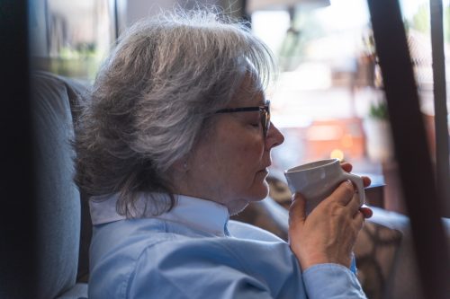 femeie mirosind o ceașcă de cafea