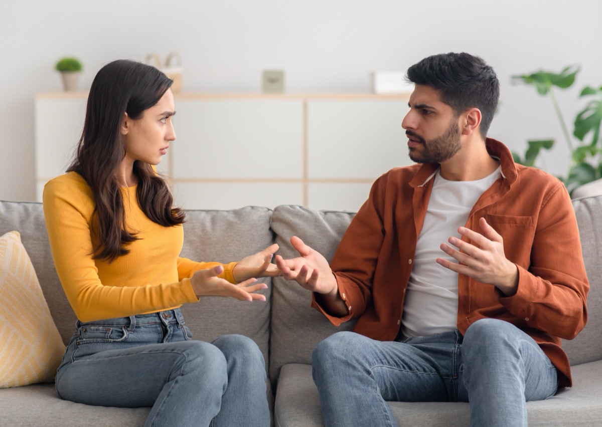 Wütende Paare, die sich streiten, streiten und einander anschauen, sitzen zu Hause auf dem Sofa.  Häusliche Gewalt und Missbrauch.  Das Paar kämpft mit dem Konzept der Ehekrise