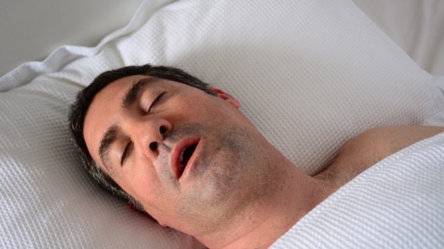 middle-aged man snoring in bed