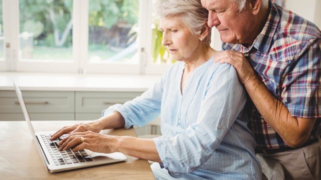 elderly couple looking concerned at laptop