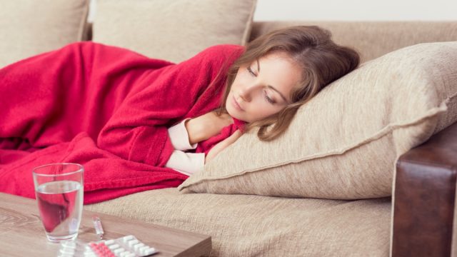 woman lying on couch while sick