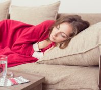 woman lying on couch while sick