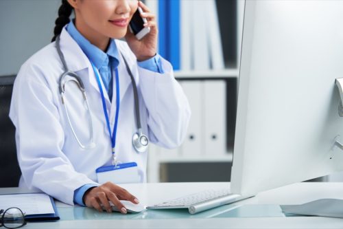 doctor on phone with patient at computer