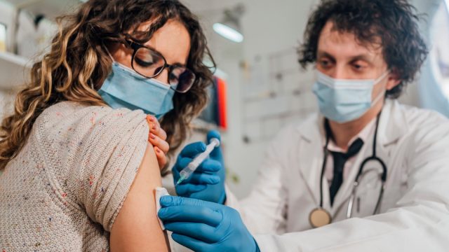 Young woman receiving a vaccine from her doctor