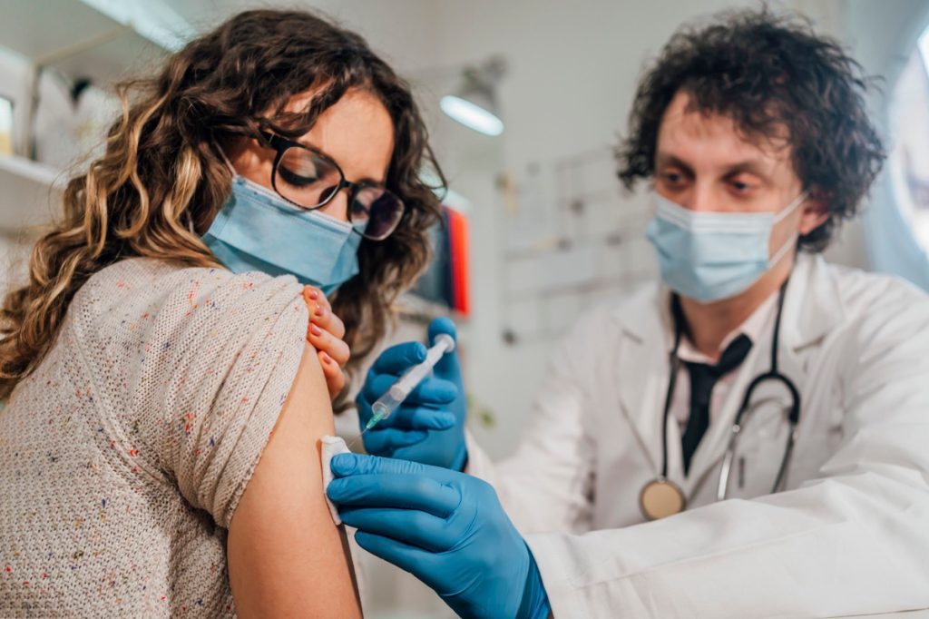 Young woman receiving a vaccine from her doctor