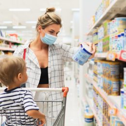 New normal in shopping. Young mother wearing prevention mask and her little son in a supermarket during virus pandemic.